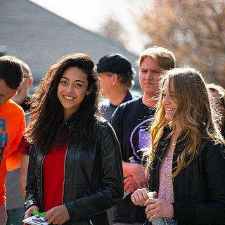 一群学生聚集在外面. 一个女学生对着镜头微笑.